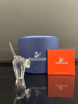 une figurine en cristal représentant un cheval, posée sur une table à côté d'une boîte de Swarovski