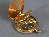a gold pocket watch sitting on a gray surface