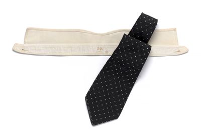 cravate à pois noirs et blancs avec un porte-cravate en bois sur fond blanc