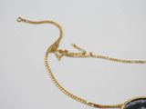 a close up of a gold necklace with a black stone on it