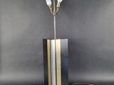 une lampe de table noire et dorée surmontée de trois ampoules
