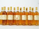 six bouteilles de vin sont alignées sur une surface blanche