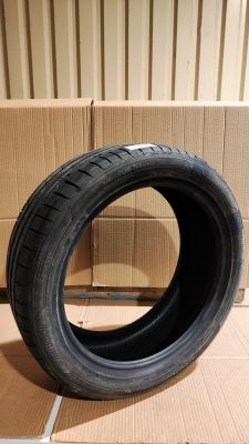 un pneu posé par terre devant une boîte en carton, avec une autre boîte en carton en arrière-plan
