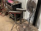 a fan sitting next to a chair in a garage