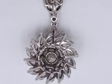a close up of a silver necklace with a flower on it