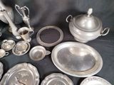 a lot of silver plates and bowls on a table
