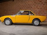 a yellow car that is parked in front of a brick wall