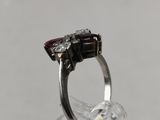 silver ring with garnetts and diamonds on top of a clear glass
