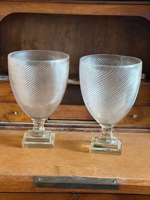 pair of clear glass goblets sitting on top of a wooden dresser