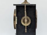 a black and gold clock on a stand on a white background