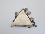 silver triangle shaped pendant with coins and a chain on a white surface