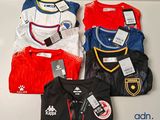 four soccer shirts on a shelf with tags on them