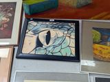 many framed pictures on a table with a vase of flowers