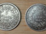 two silver coins sitting side by side on a wooden surface