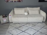 un canapé blanc placé dans un salon, à côté d'un tapis