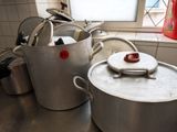 Plusieurs casseroles et poêles sont posées sur un plan de travail dans une cuisine.