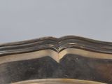 an antique silver plate with a curved edge on a table