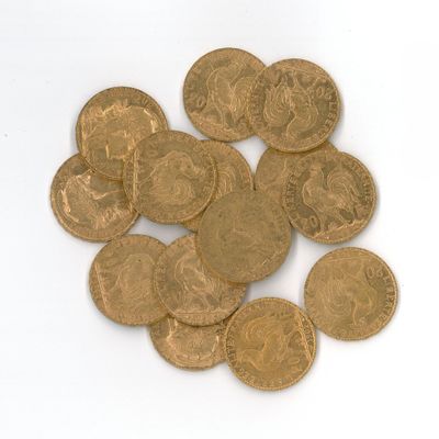 quelques pièces d'or posées sur une surface blanche, sur fond blanc
