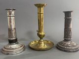 trois chandeliers en argent et en or posés les uns à côté des autres sur une table