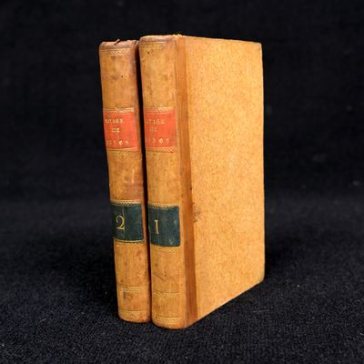 two old books sitting on top of each other on a black surface