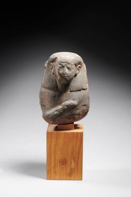 une statue en pierre représentant un sphinx posée sur un bloc de bois