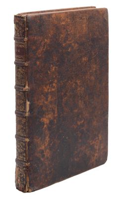 un vieux livre à la couverture brune posé sur une surface blanche