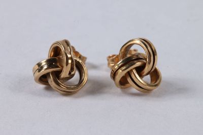 une paire de boucles d'oreilles dorées ornées d'un motif en forme de nœud
