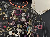 many different necklaces and bracelets on the table