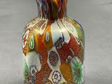 a colorful vase sitting on a table with a gray background