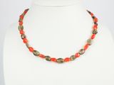 un collier composé de perles rouges et vertes sur un mannequin blanc