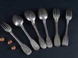 six forks and spoons with nuts on a black surface