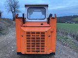 un tracteur orange garé sur un chemin de terre