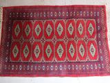 an old red rug with a diamond design on it on a white floor