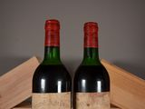 two bottles of red wine sitting on top of a wooden crate