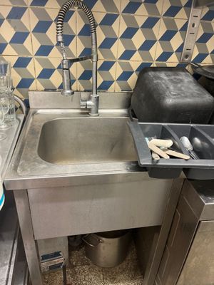 a sink in a kitchen with a trash can and a trash can