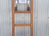 une échelle en bois appuyée contre un mur, sur laquelle est accrochée une pancarte