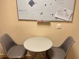 two chairs and a table with a white board on the wall