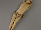 une figurine en ivoire représentant Jésus sur la croix, posée sur une surface grise