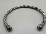 a close up of a silver bracelet on a white surface