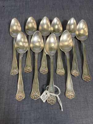 six cuillères en argent et une paire de ciseaux posés sur une table