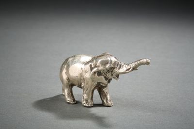 une figurine d'éléphant en argent posée sur une surface grise