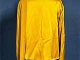 a yellow jacket on a mannequin stand against a blue wall