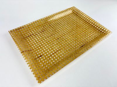 a gold tray with holes on it on a white surface