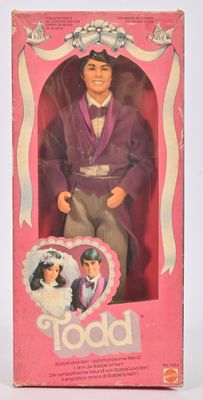 La poupée qui se trouve dans la boîte porte un costume violet et un nœud papillon.
