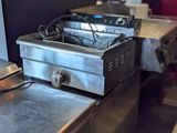 un plan de travail en métal sur lequel est posée une friteuse, dans une cuisine