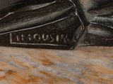 statue of a man with a hat and bow tie sitting on a marble slab