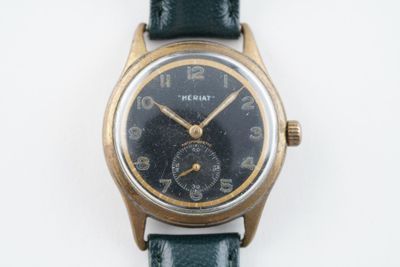 une montre-bracelet en or avec un cadran noir sur un bracelet vert