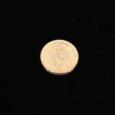 a close up of a gold coin on a black surface