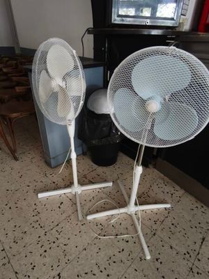 deux ventilateurs blancs posés sur le sol devant une télévision