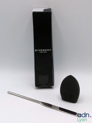un gros plan d'une éponge de maquillage noire à côté d'un pinceau noir